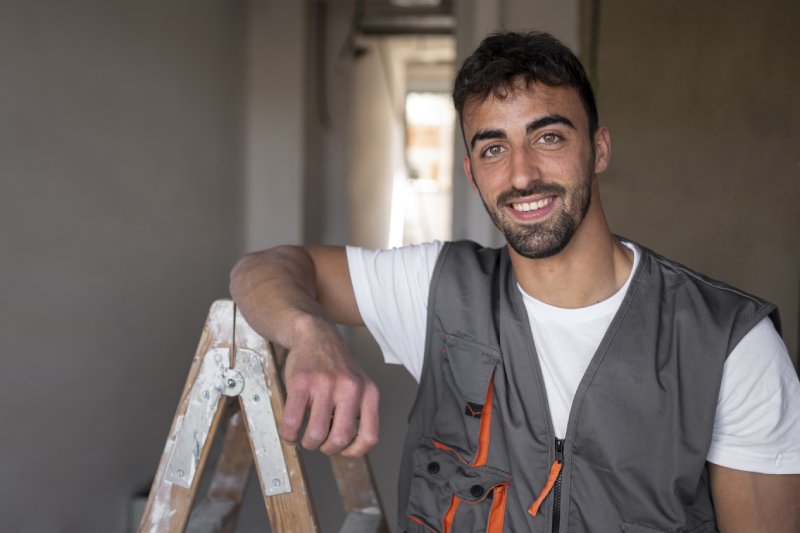 Smiling contractor with ladder ready to make repairs before selling a house in California