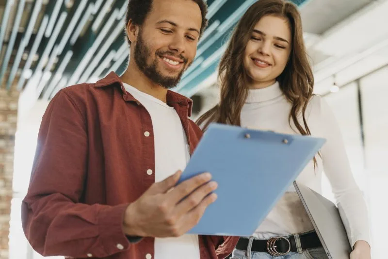 Young couple reviewing inherited property documents and estate planning paperwork together, smiling