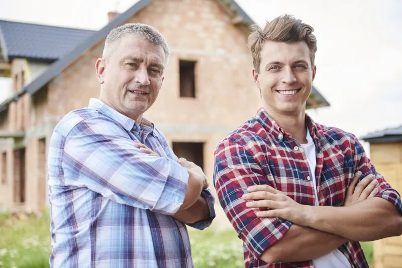 Father and adult son standing together in front of the California family home inheritance