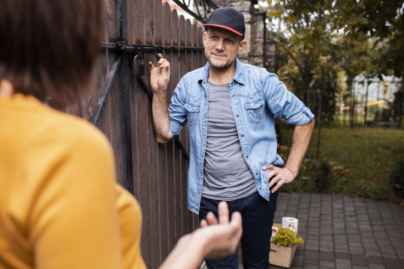 Neighbors discussing a boundary dispute near a shared fence to resolve a property encroachment problem