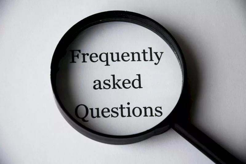 Magnifying glass highlighting the words ‘Frequently Asked Questions’ on white paper, symbolizing clarity and answers in a real estate FAQ section