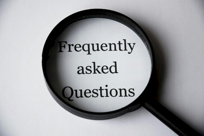 Magnifying glass highlighting the words ‘Frequently Asked Questions’ on white paper, symbolizing clarity and answers in a real estate FAQ section