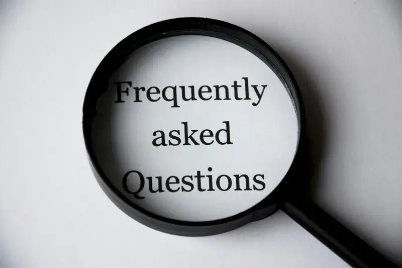 Magnifying glass highlighting the words ‘Frequently Asked Questions’ on white paper, symbolizing clarity and answers in a real estate FAQ section