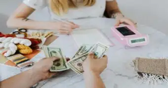 Person counting cash at a table while calculating home repair estimates.