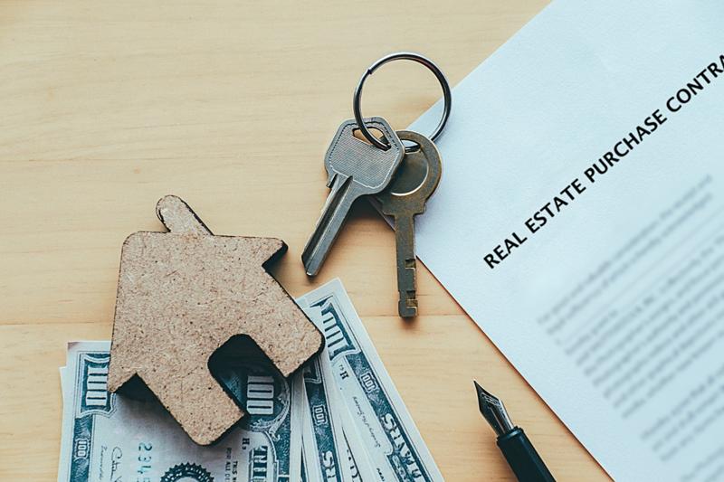House cutout, keys, and contract representing home selling costs.