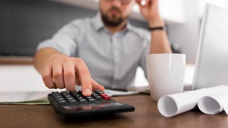 Man using calculator at desk, showing how to minimize losses.