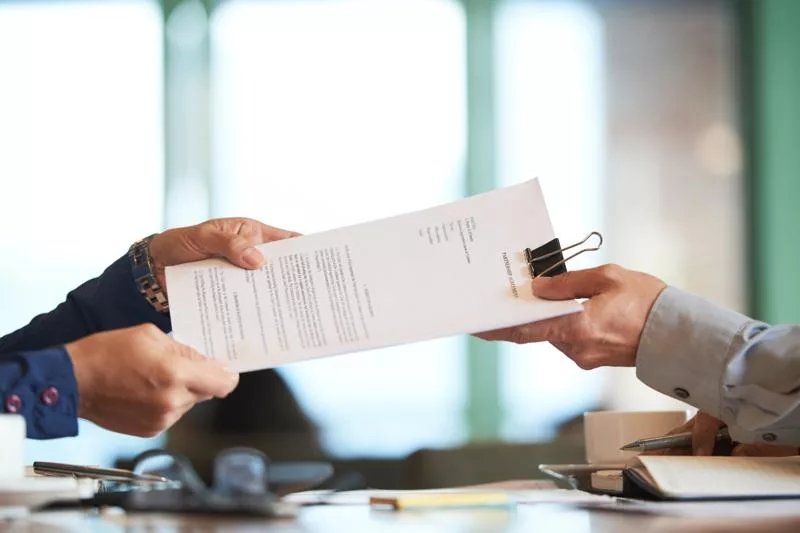 Two people exchange legal documents during a probate property sale.