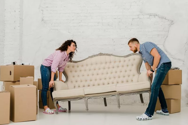 Couple lifting a vintage sofa while clearing out a home.