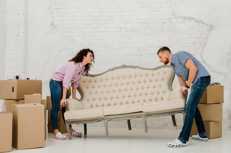 Couple lifting a vintage sofa while clearing out a home.
