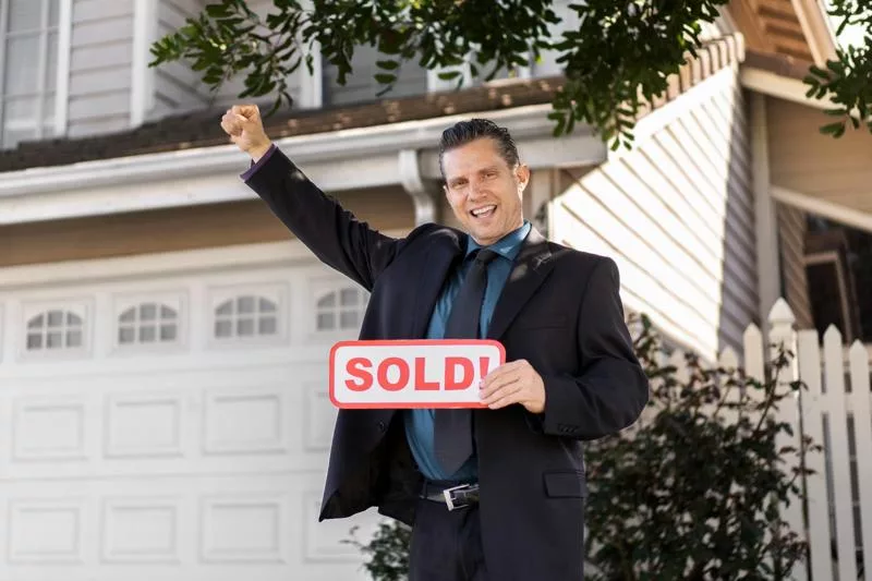 Happy seller holding sold sign after selling home to Osborne Homes.