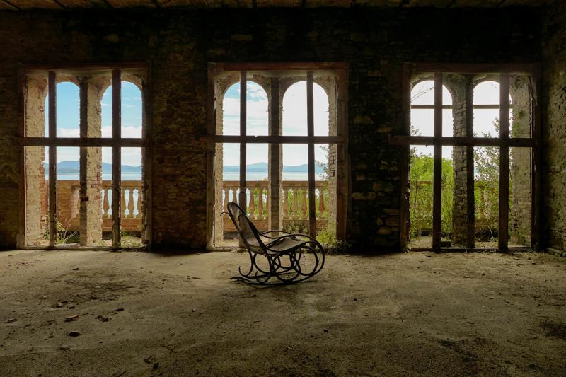 Abandoned house with rocking chair inside and broken windows.