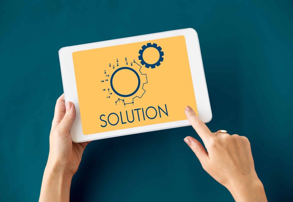 Hands holding tablet with gears and the word solution displayed.