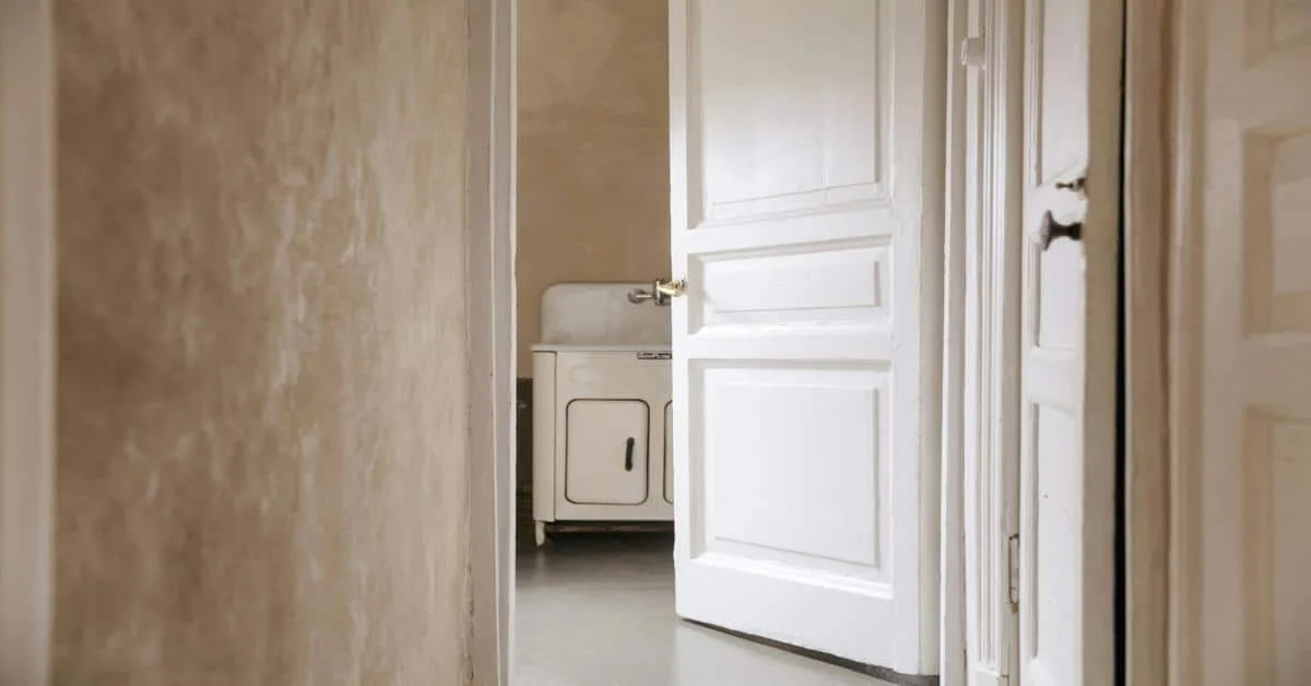 Interior hallway with open white-painted door and vintage sink