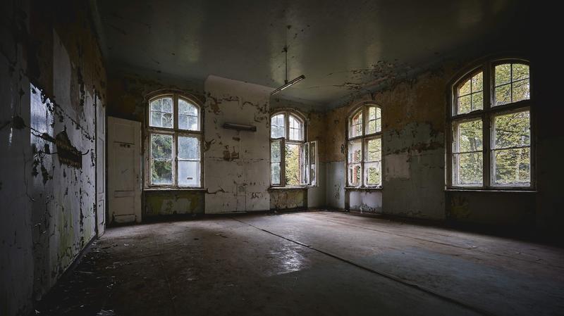 Interior of vacant abandoned house showing peeling paint and floor damage