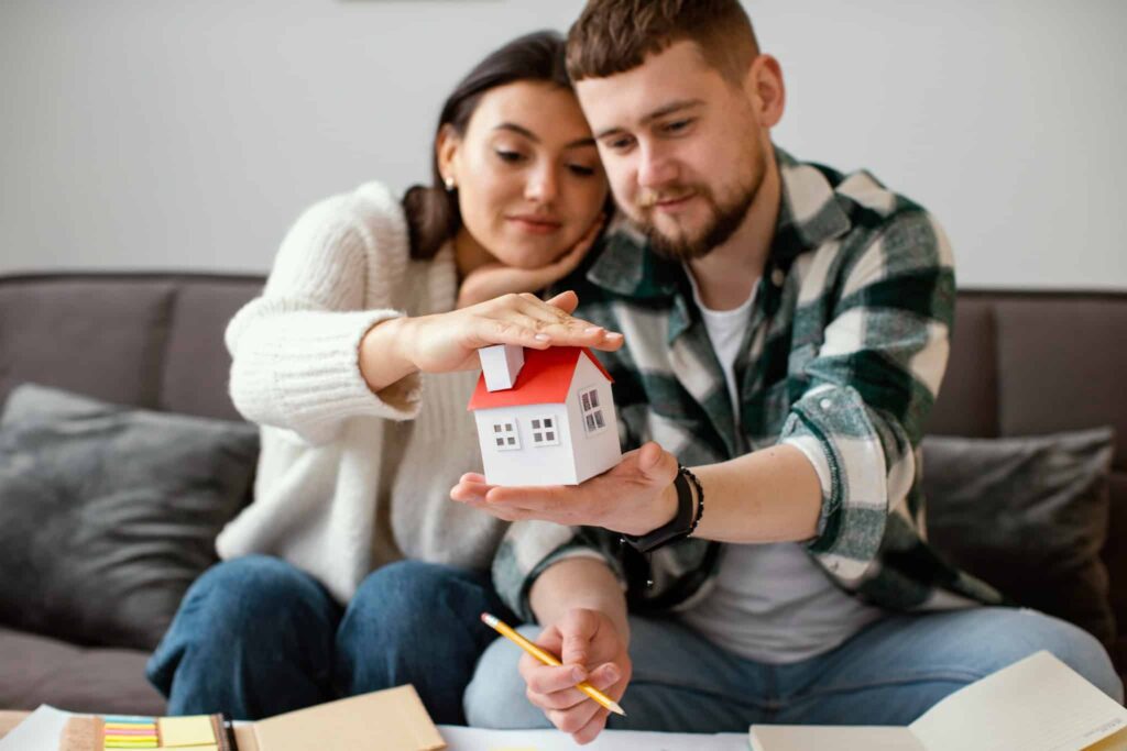 A couple holding a house model while deciding whether to offer rent-to-own.