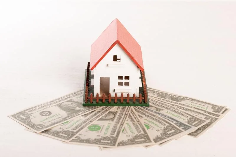 Mini house model with cash spread out underneath