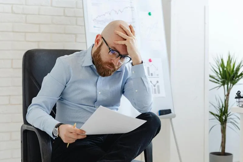 Stressed man reviewing documents after his house sale contract fell through