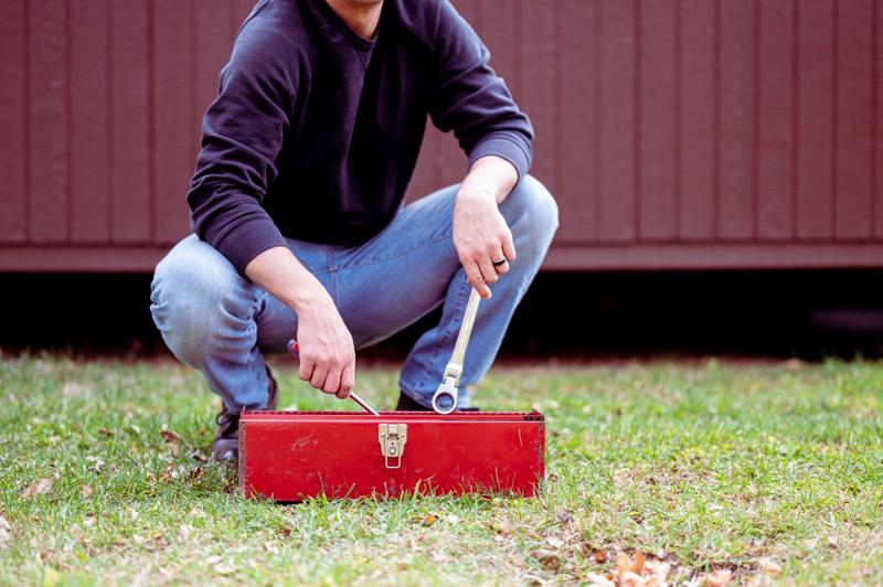 Man with tools preparing for home repair on grass