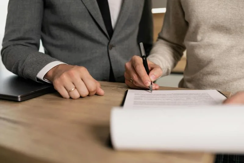 Person signing a real estate purchase agreement at a desk