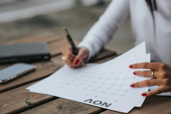 A woman sitting at a table with a monthly calendar planning to sell a house