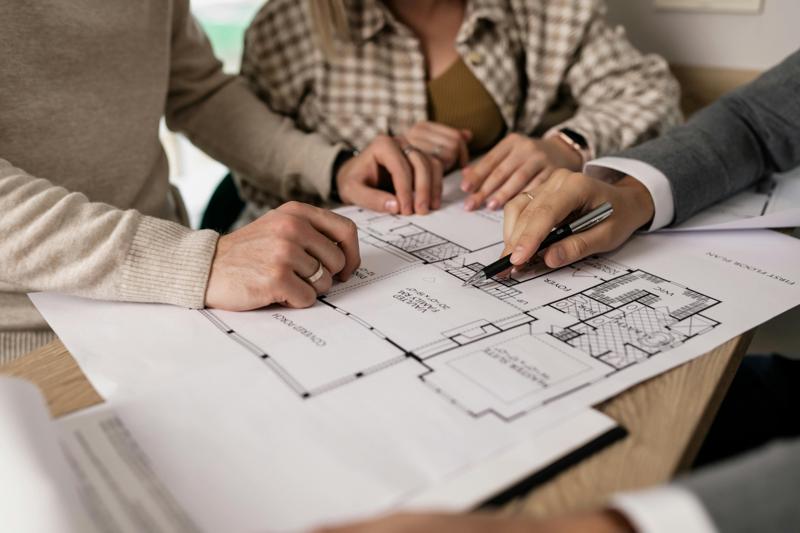 People reviewing architectural house plans with pen and paper