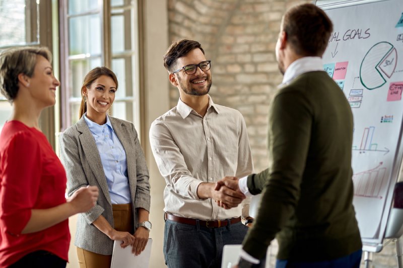 Team shaking hands in meeting, discussing California real estate commissions.