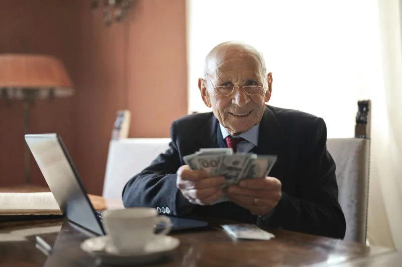 Older man smiling with cash, symbolizing fast cash home offers