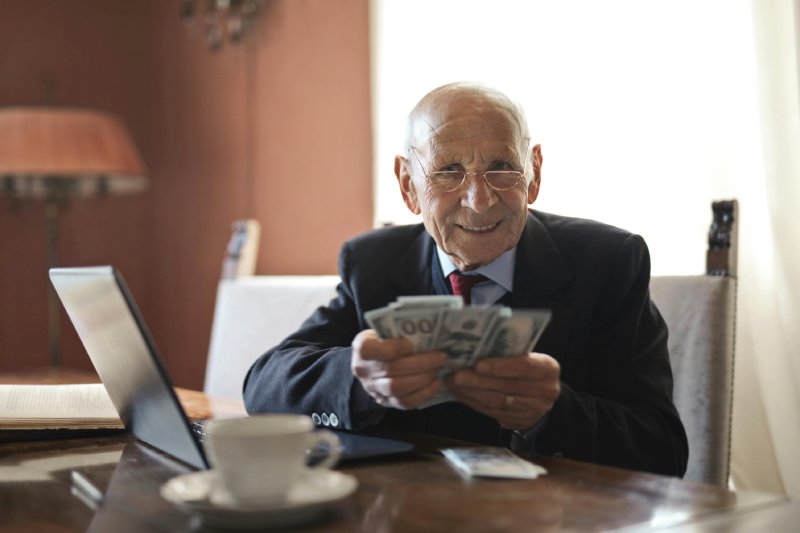 Older man smiling with cash, symbolizing fast cash home offers