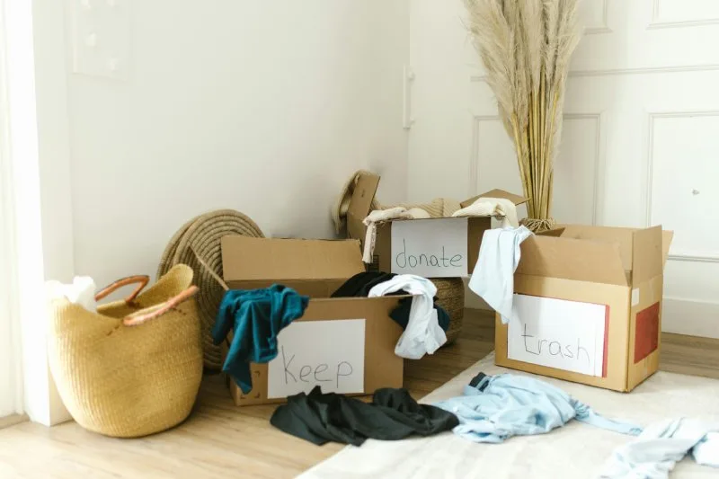 Cardboard boxes labeled keep, donate, trash used for decluttering.