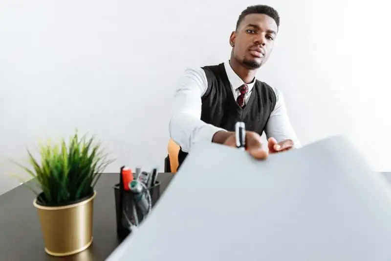 Man in business attire offers tax documents across his desk.