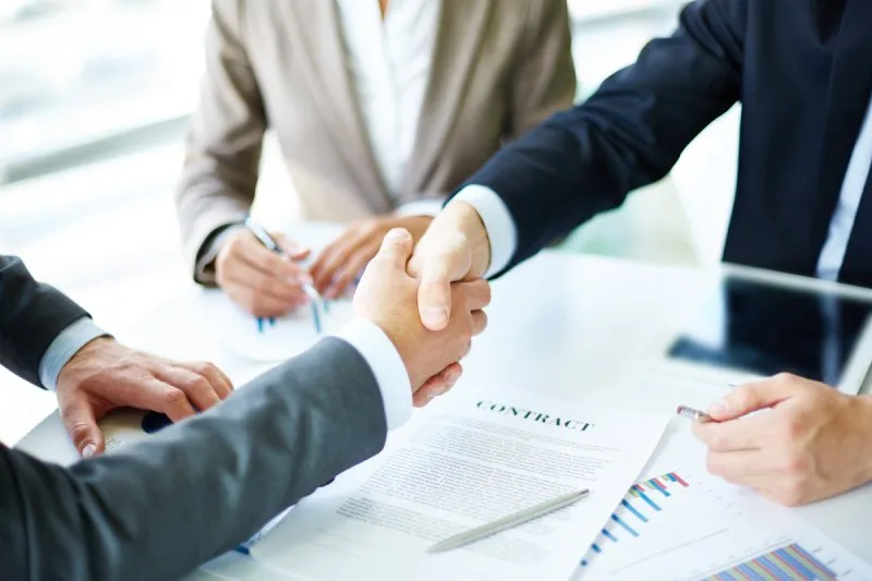 Handshake over signed contract, symbolizing commission-free home sale agreement.