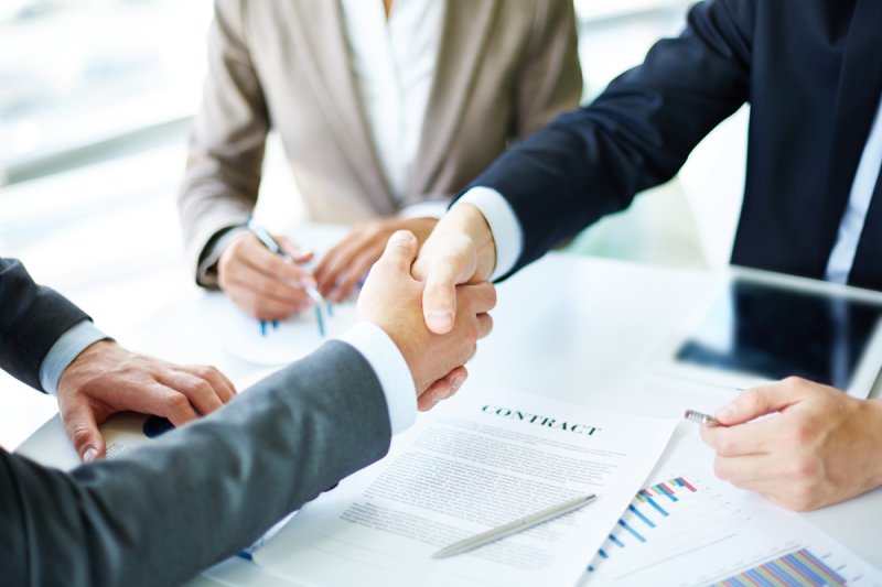 Handshake over signed contract, symbolizing commission-free home sale agreement. 