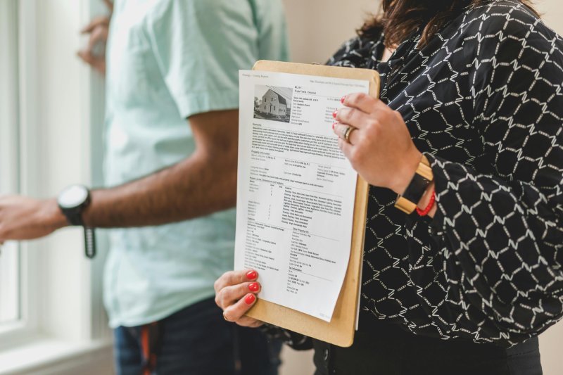 Real estate agent holding property listing sheet during home showing.
