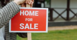 Red home for sale sign outside property with no buyers.