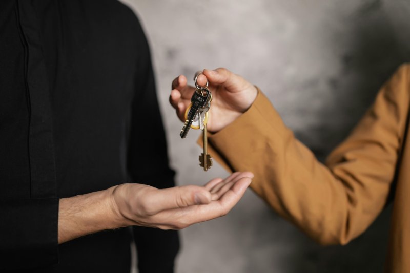 Person handing over house keys, representing final home sale solution.