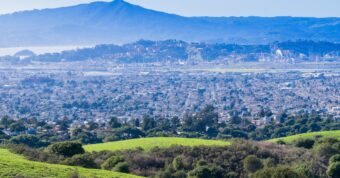Aerial view of Contra Costa County with hills, housing, and industrial areas showing the regional real estate market.