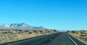 Open desert highway leading toward mountains near Ridgecrest, California, representing local real estate and housing market.
