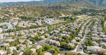 Panoramic view of Santa Clarita residential neighborhoods with curved streets, homes, and San Gabriel Mountains foothills.